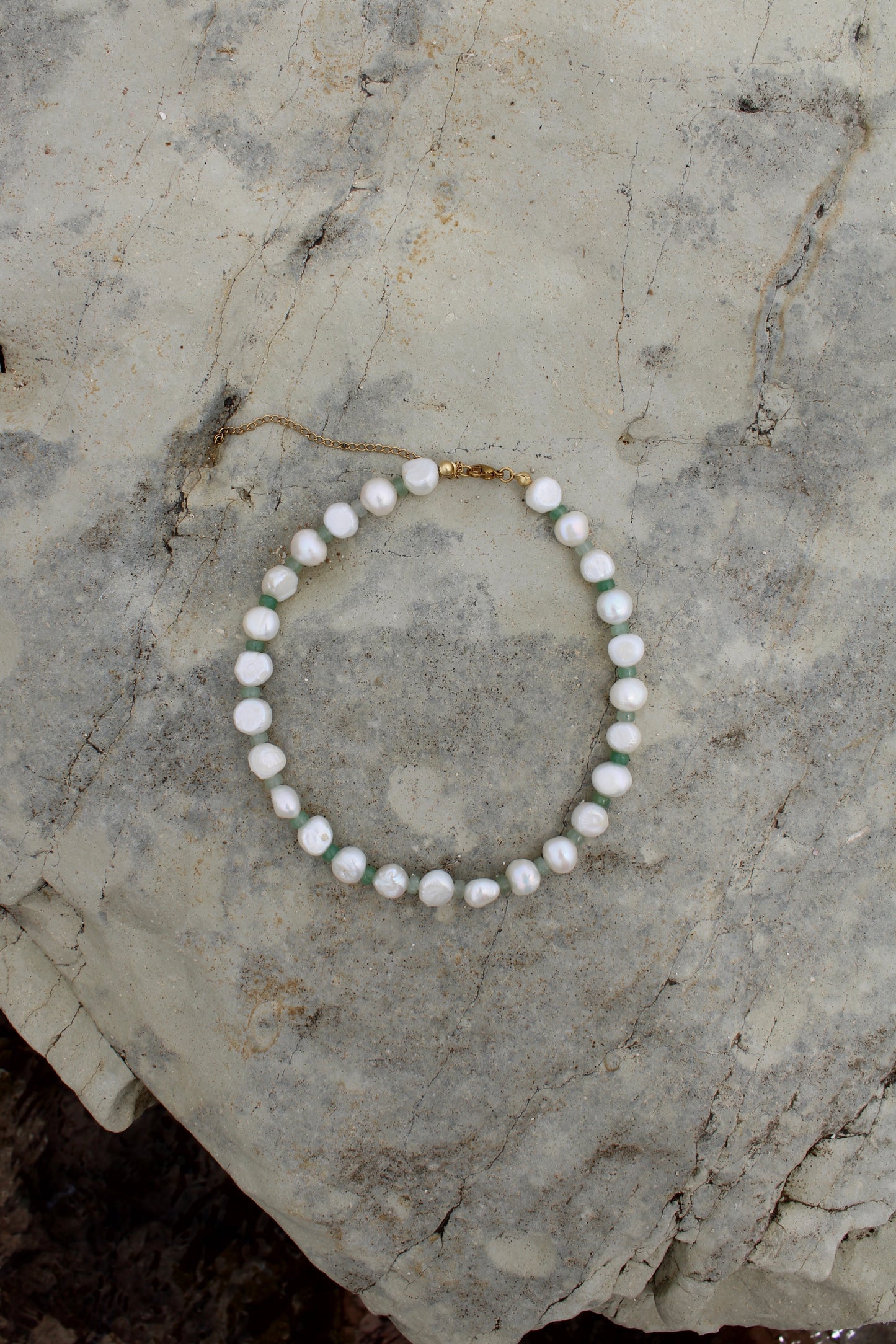 Elegant white freshwater pearl necklace featuring a motif design adorned with small green beads, adding a touch of sophistication to any ensemble.