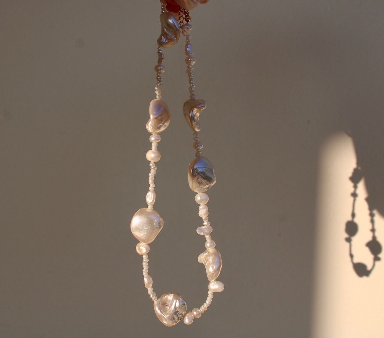 Unique mother of pearl shell necklace featuring a blend of small and large pearls, adding a distinctive touch to your look.