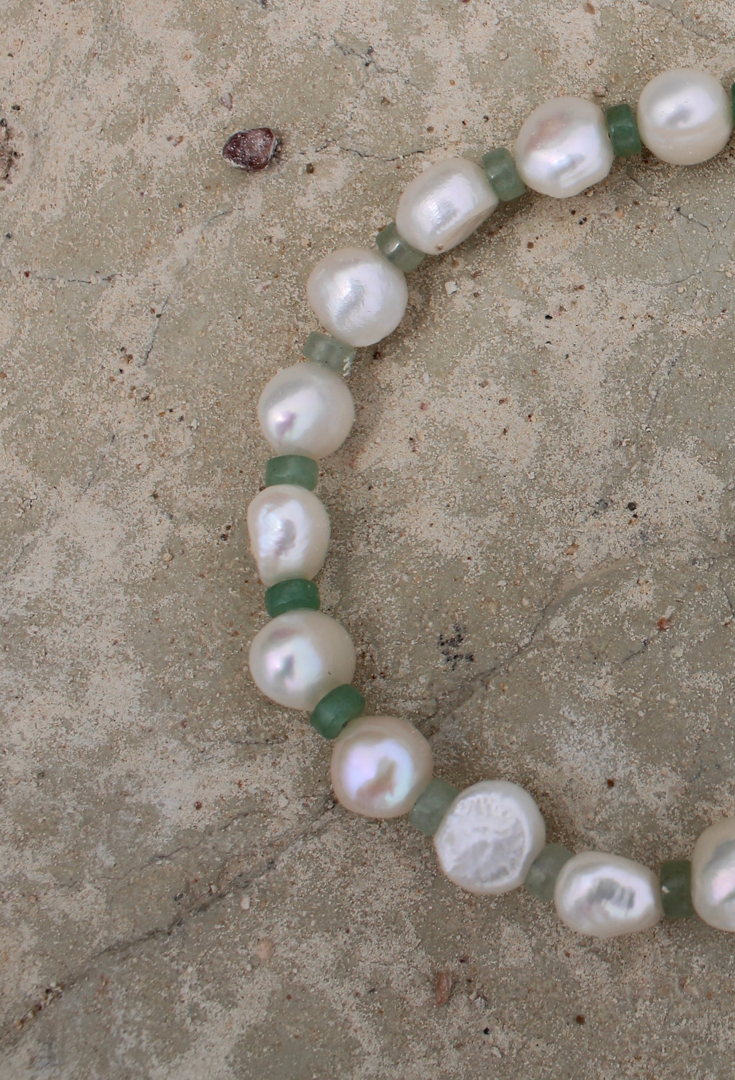 Elegant white freshwater pearl necklace featuring a motif design adorned with small green beads, adding a touch of sophistication to any ensemble.