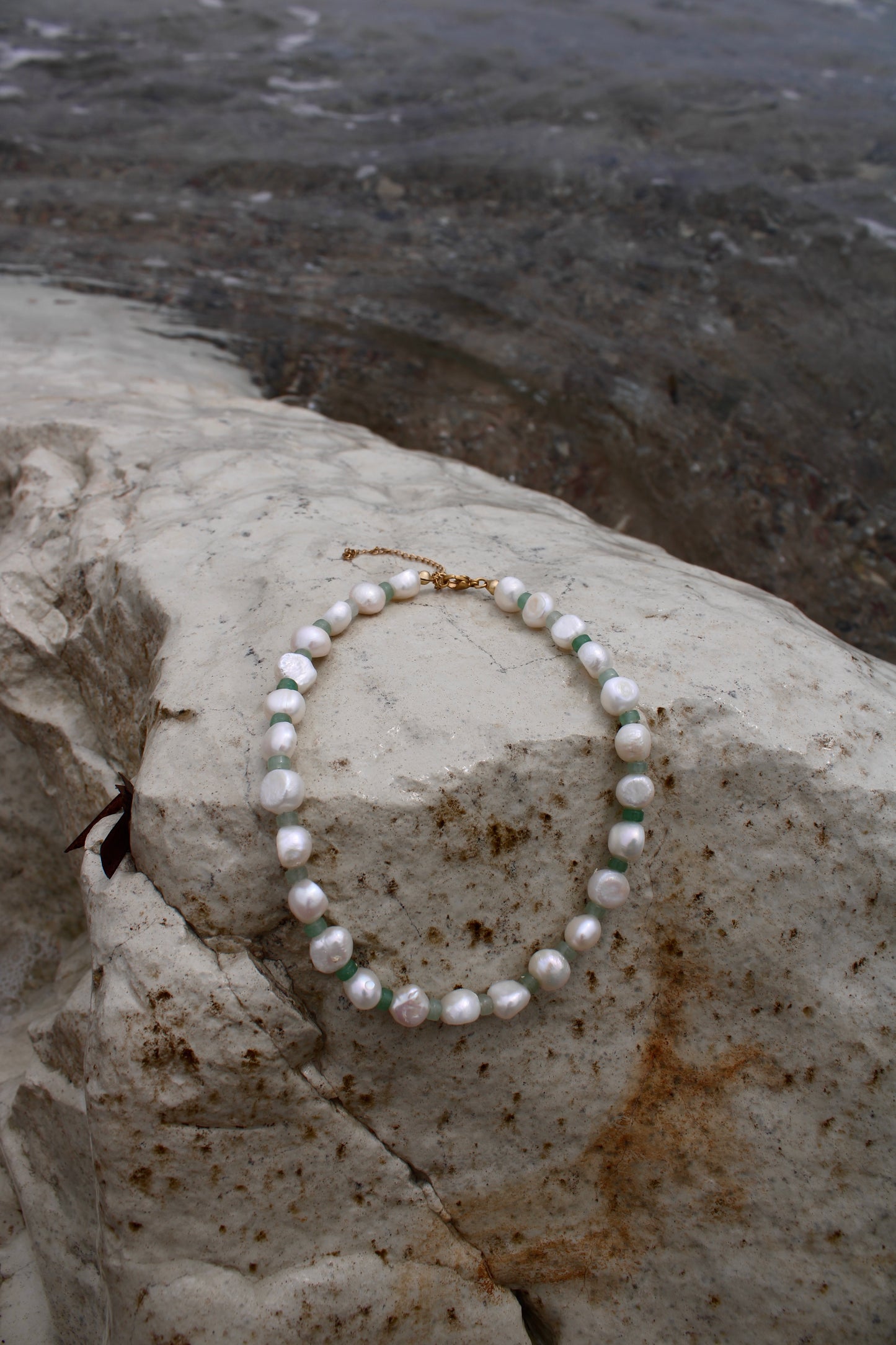 Elegant white freshwater pearl necklace featuring a motif design adorned with small green beads, adding a touch of sophistication to any ensemble.